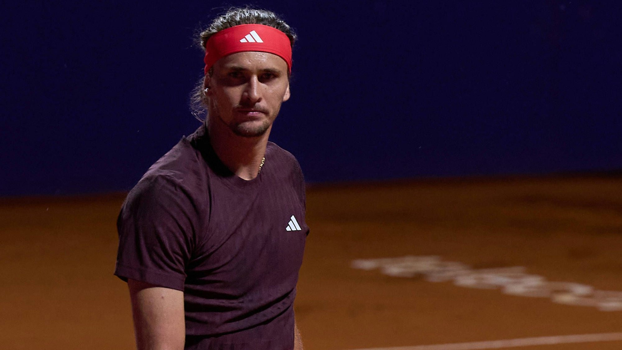 Alexander Zverev steht auf dem Tennisplatz und schaut grimmig in die Kamera.