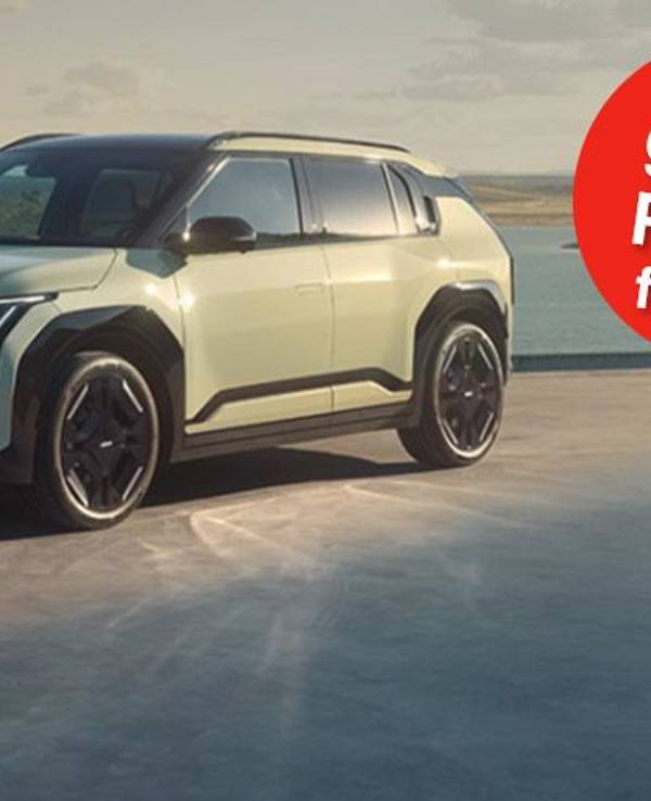 Ein Kia EV3 GT-line steht auf einer Betonfläche vor einem See und einer grünen Hügellandschaft.
