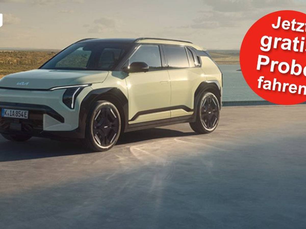 Ein Kia EV3 GT-line steht auf einer Betonfläche vor einem See und einer grünen Hügellandschaft.
