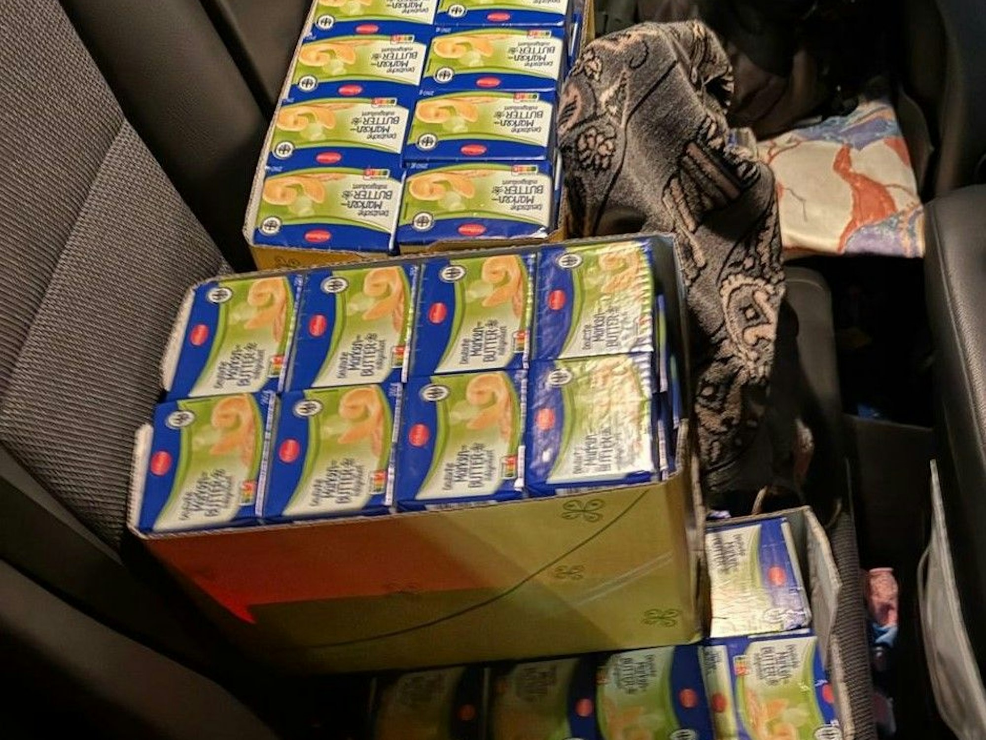 Auf dem Rücksitz eines Fahrzeugs befinden sich mehrere Pakete voll mit Butter-Päckchen.