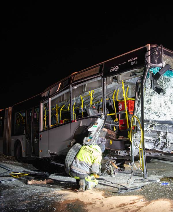 Ein Mann kniet vor einem schwer beschädigten Bus.