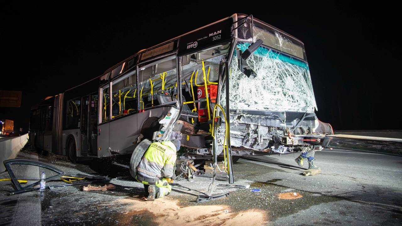 Ein Mann kniet vor einem schwer beschädigten Bus.