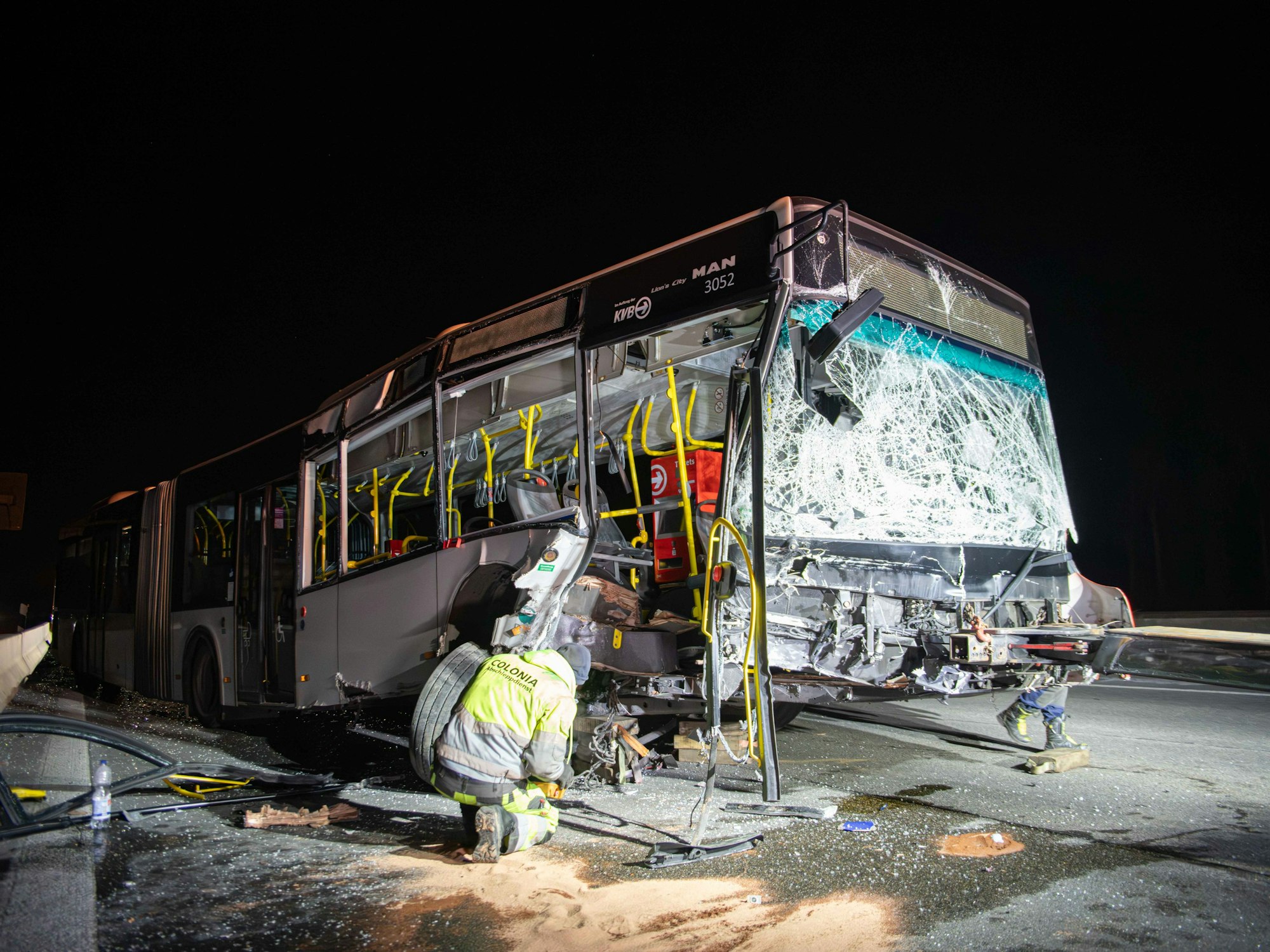 Ein Mann kniet vor einem schwer beschädigten Bus.