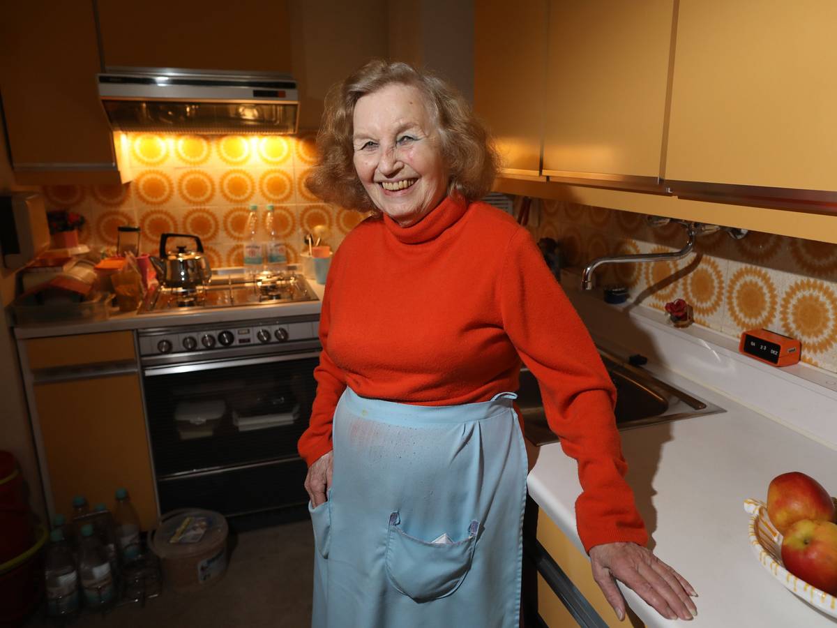 Eine alte Frau steht in ihrer Küche.