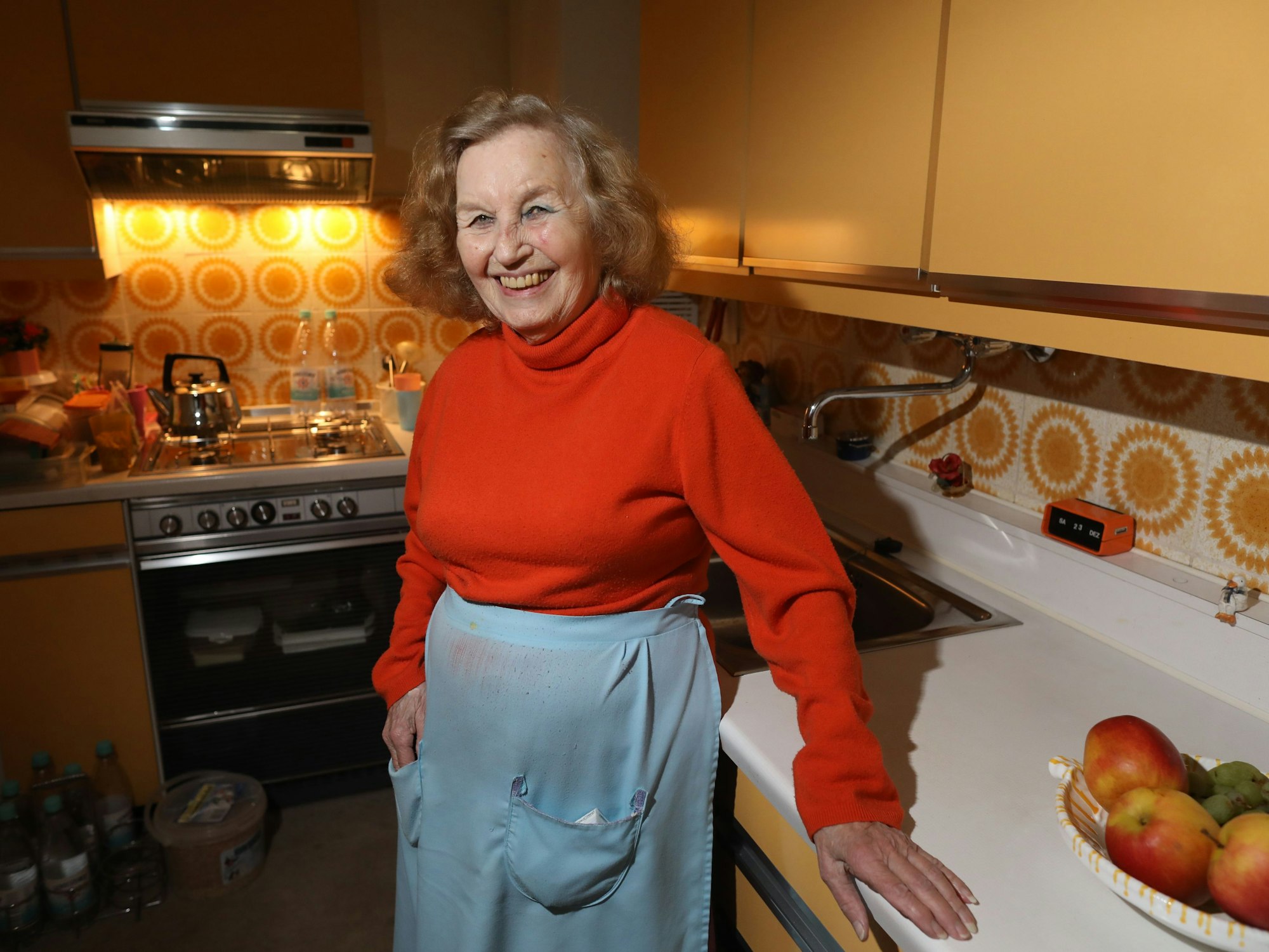 Eine alte Frau steht in ihrer Küche.