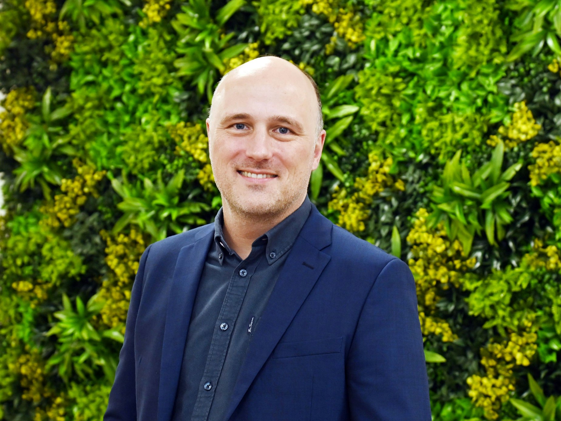 Sven Lehmann steht vor einer Hecke.