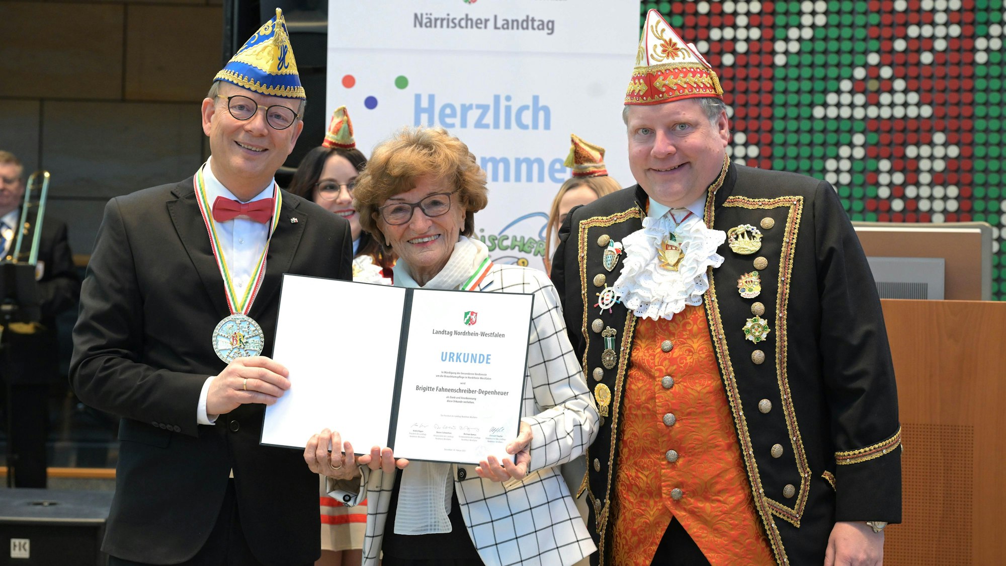 Biggi Fahnenschreiber erhält von André Kuper und Lutz Schade eine Urkunde.