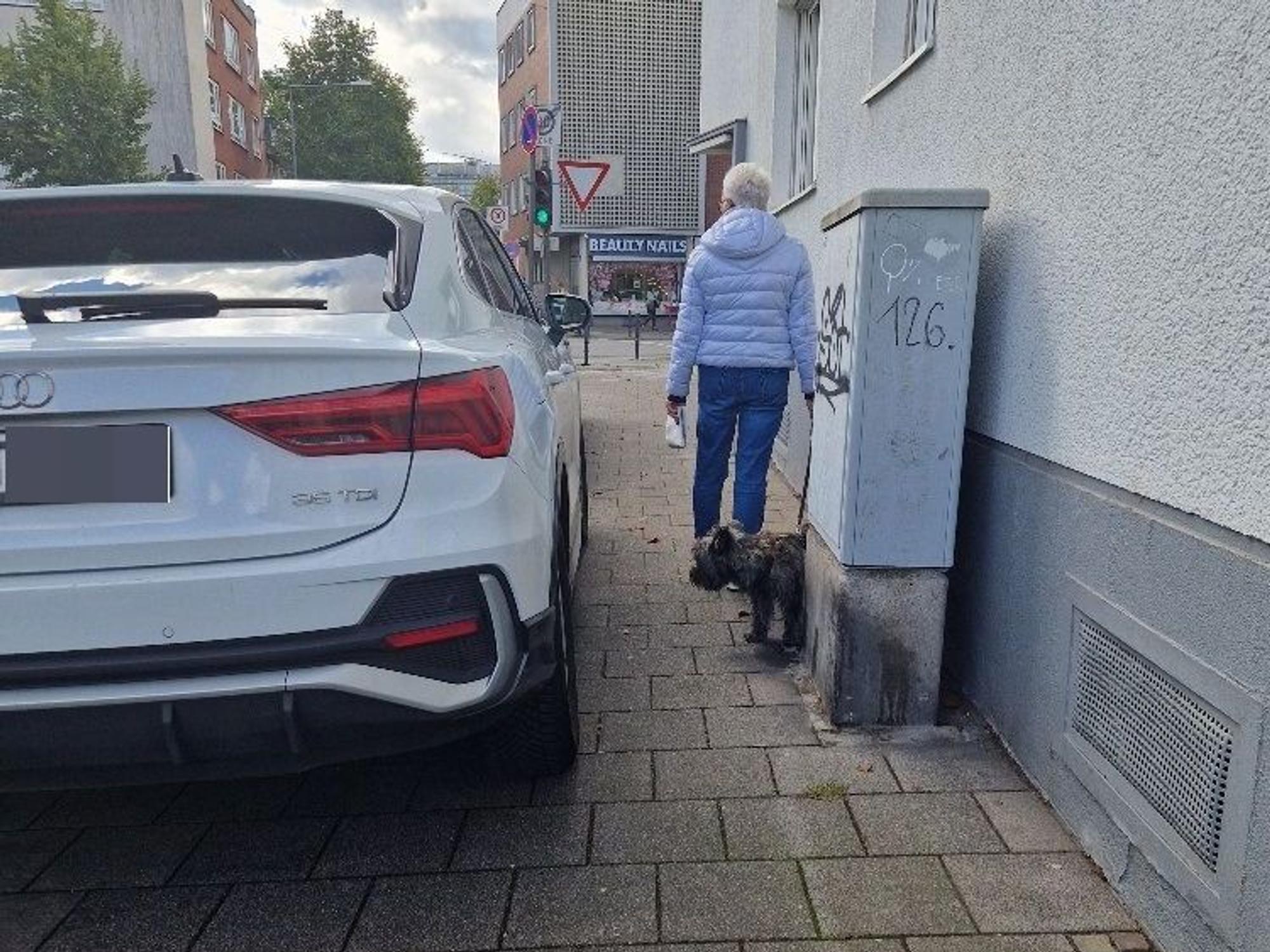 Ein SUV steht weit auf dem Gehweg.