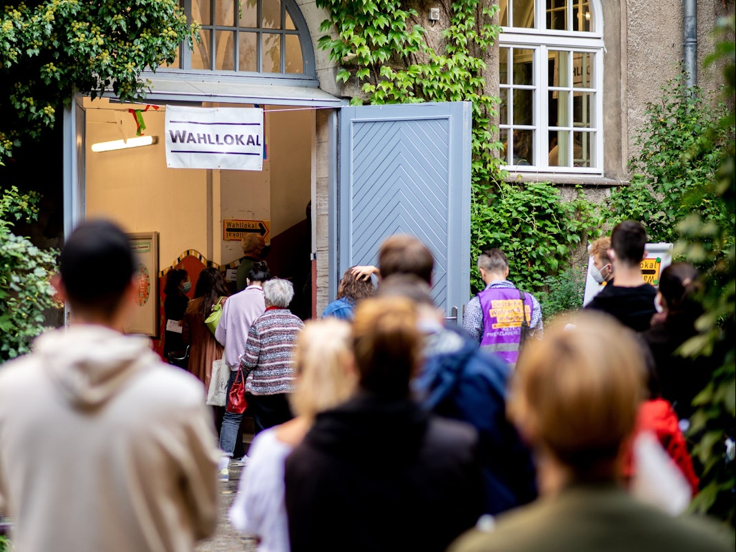 Zahlreiche Wählerinnen und Wähler warten im Berliner Stadtteil Prenzlauer Berg in einer langen Schlange vor einem Wahllokal.
