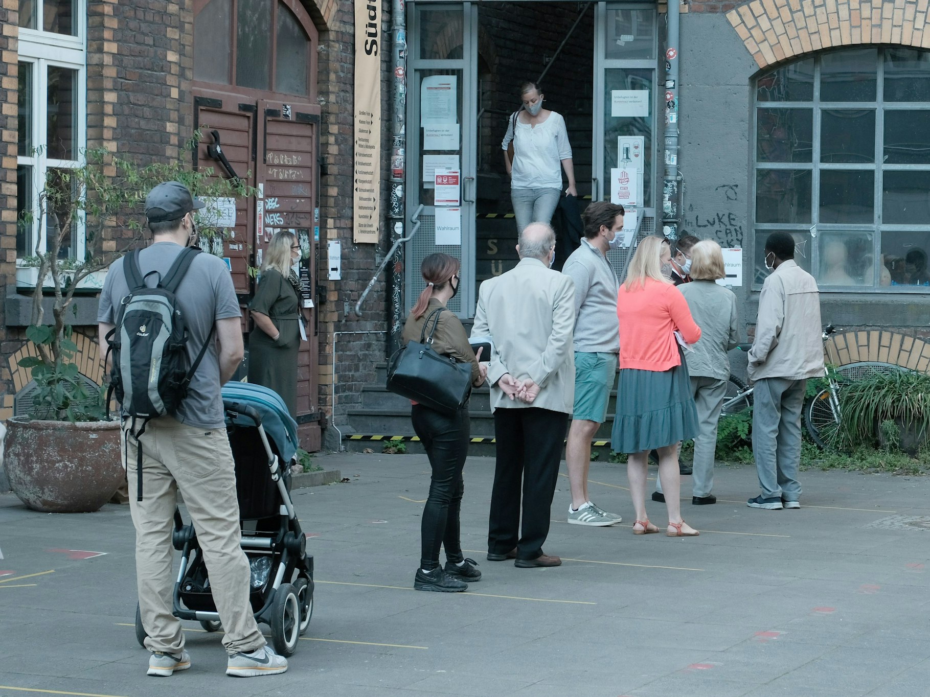 Menschen stehen vor einem Wahllokal in Köln und warten auf Einlass.
