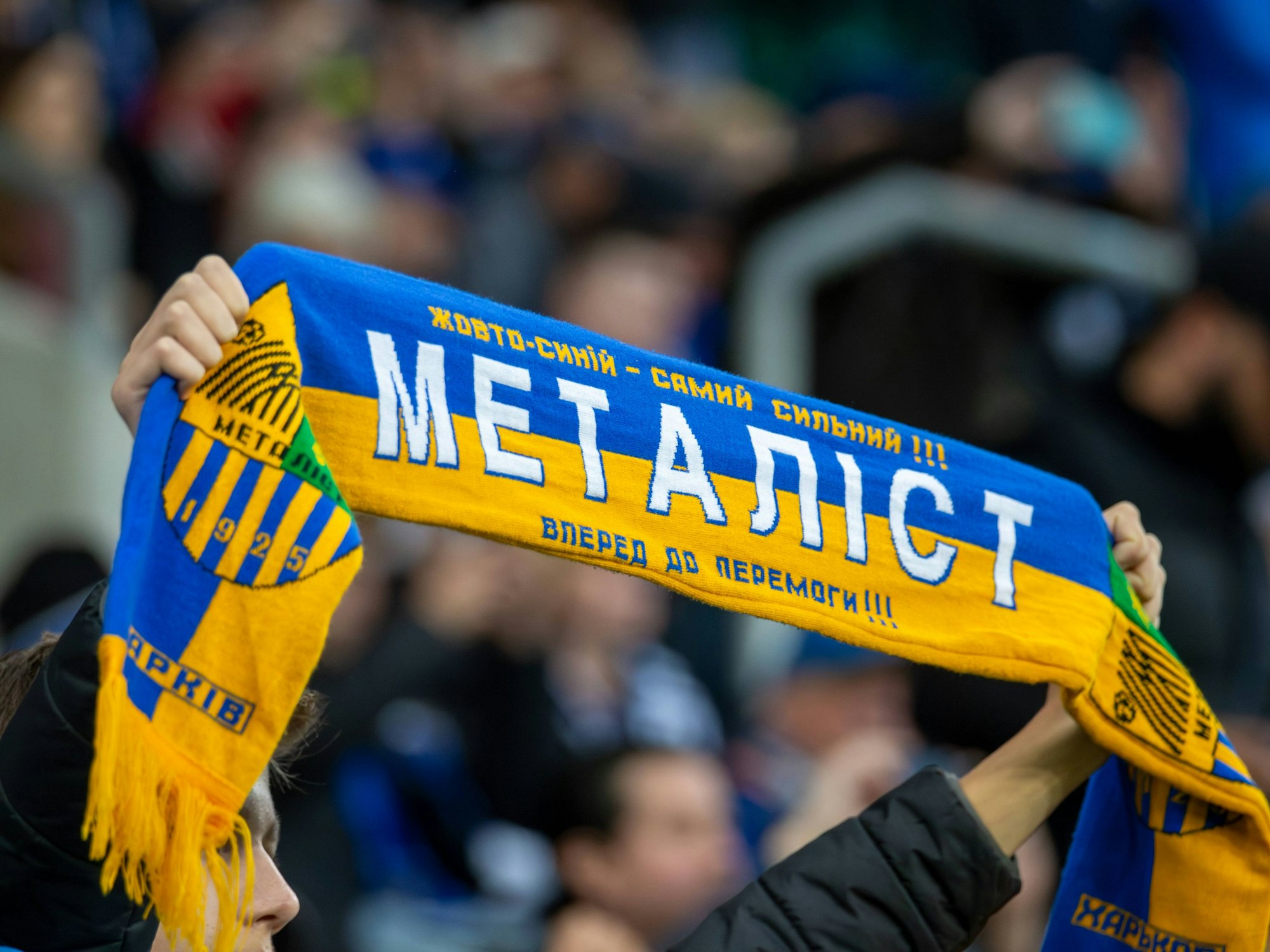 Ein Fan hält einen Schal von Metalist Charkiw nach oben.