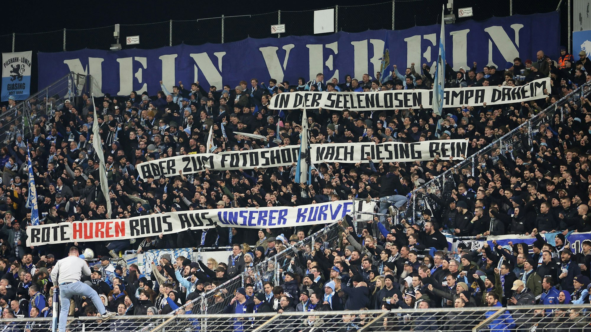 Auf einem Plakat in der Fankurve von 1860 München steht zu lesen: „In der seelenlosen Pampa daheim, aber zum Fotoshoot nach Giesing rein. Rote Hu*** raus aus unserer Kurve!“