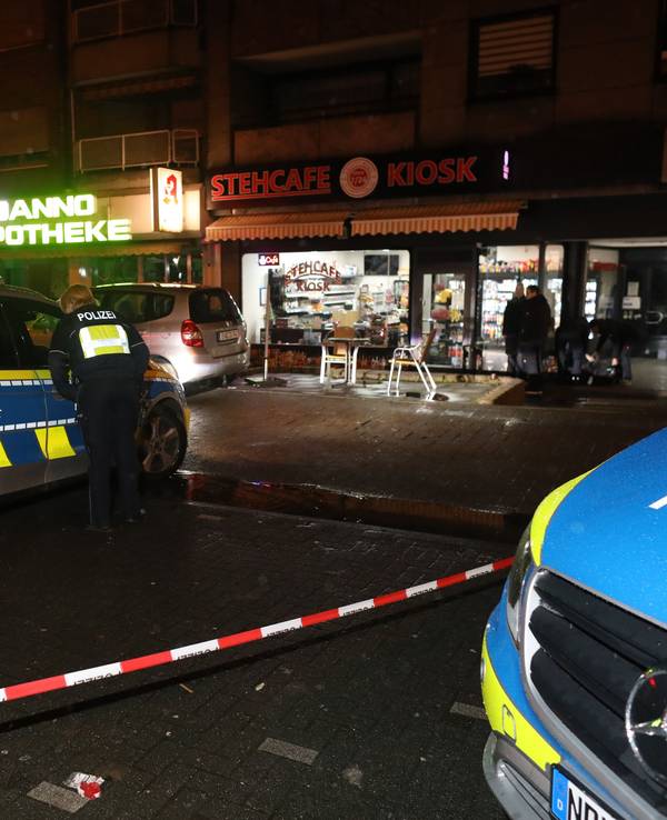 Zwei Polizeiwagen stehen auf einer abgesperrten Straße.