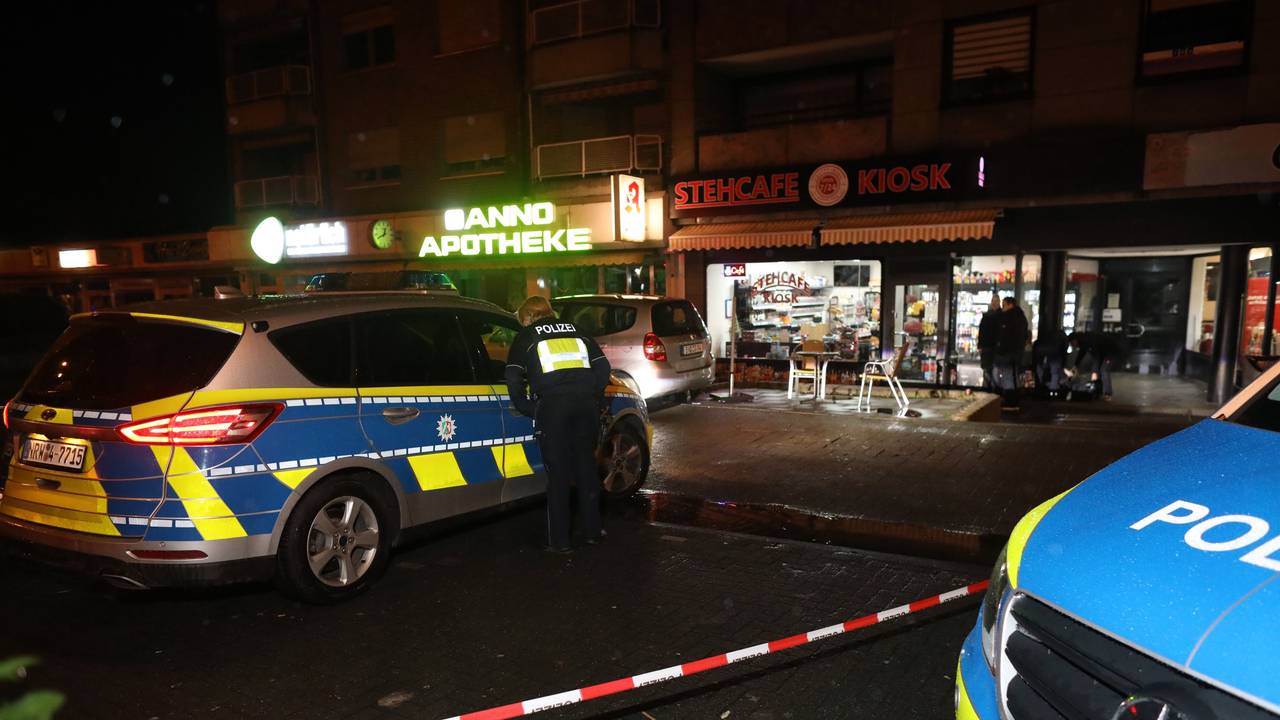 Zwei Polizeiwagen stehen auf einer abgesperrten Straße.