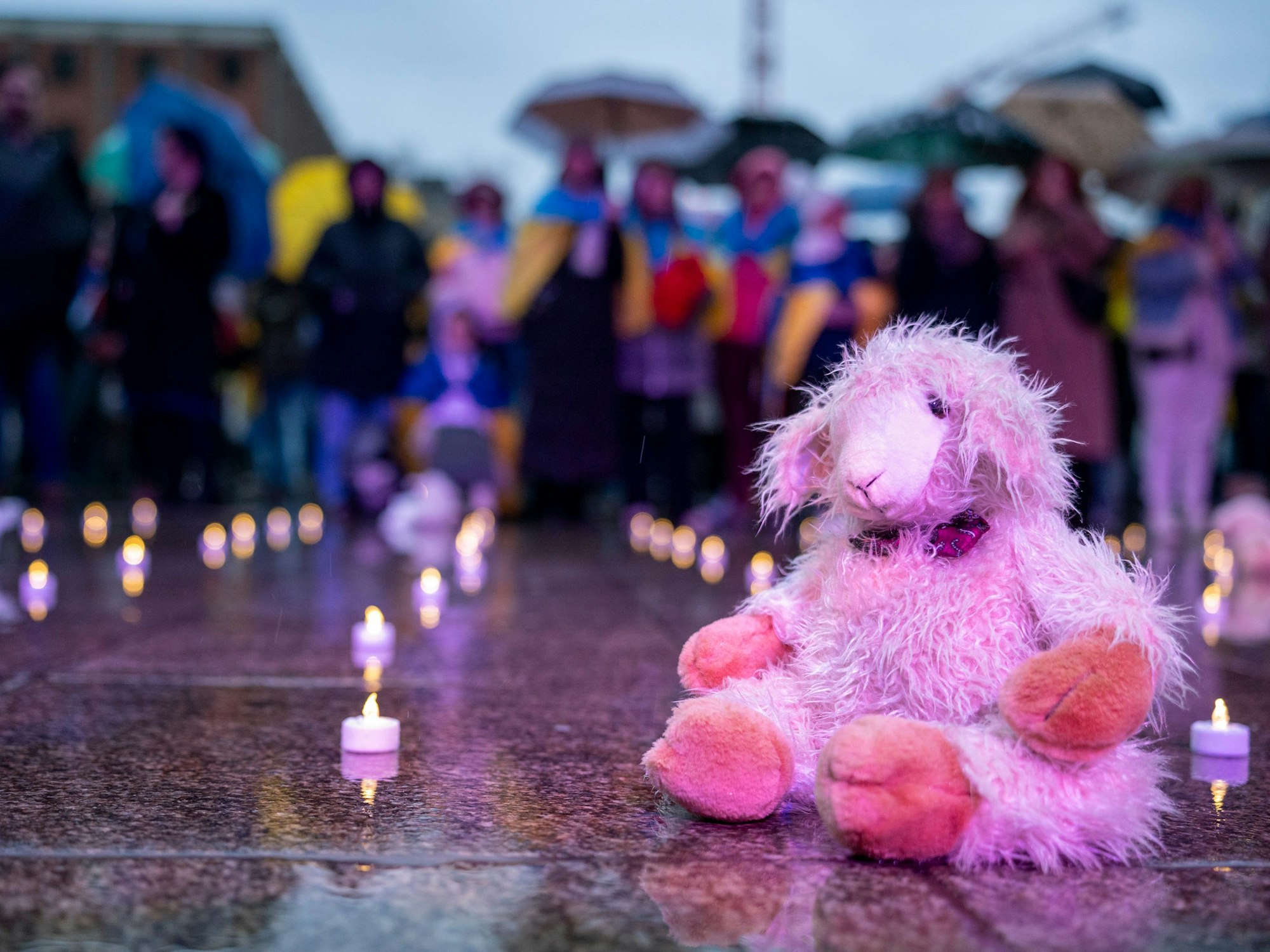 Ein Kuscheltier liegt neben Kerze auf dem Boden.
