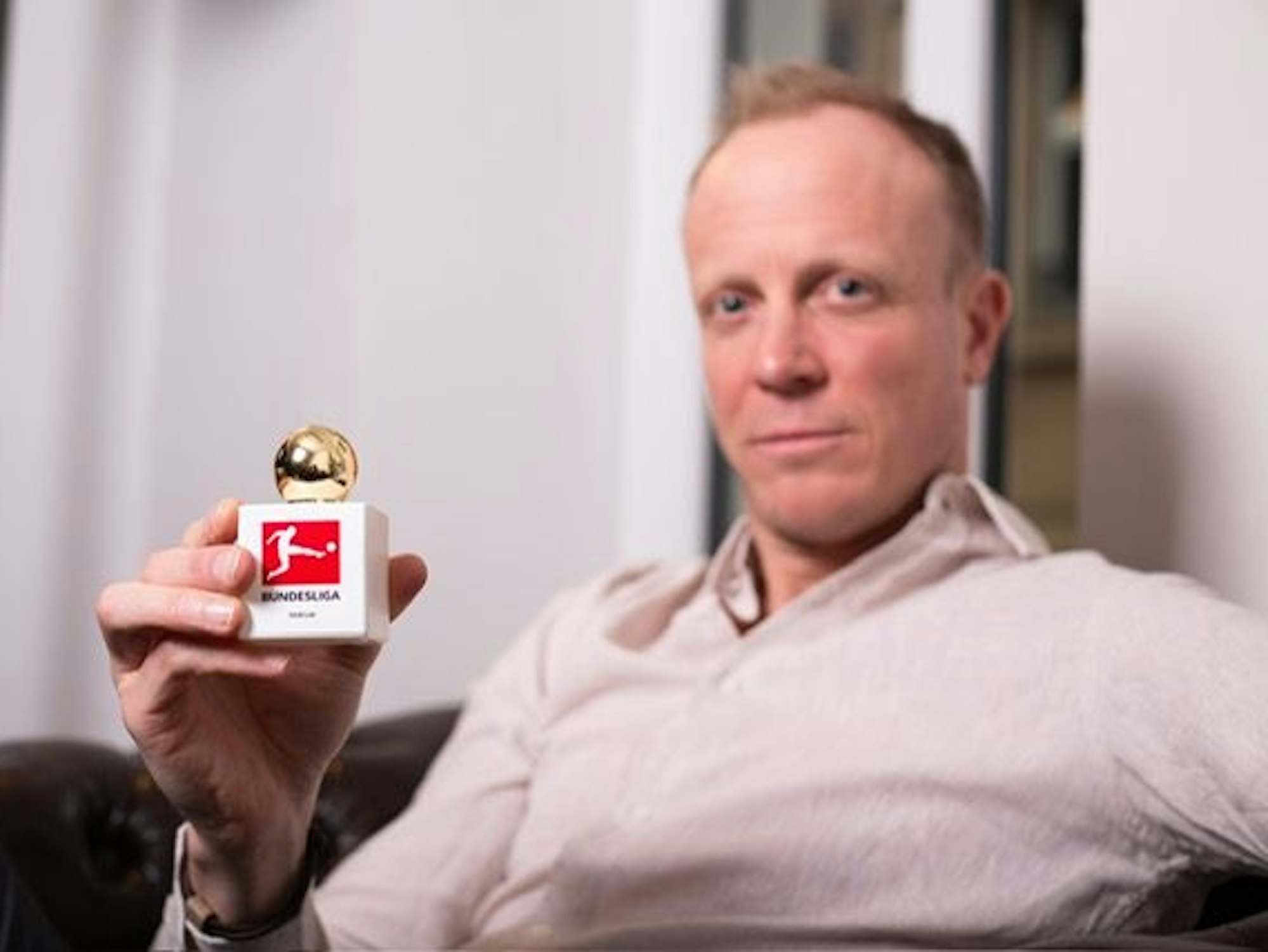 Christian Gittelmann hält einen Flakon mit Bundesliga-Logo in die Kamera.