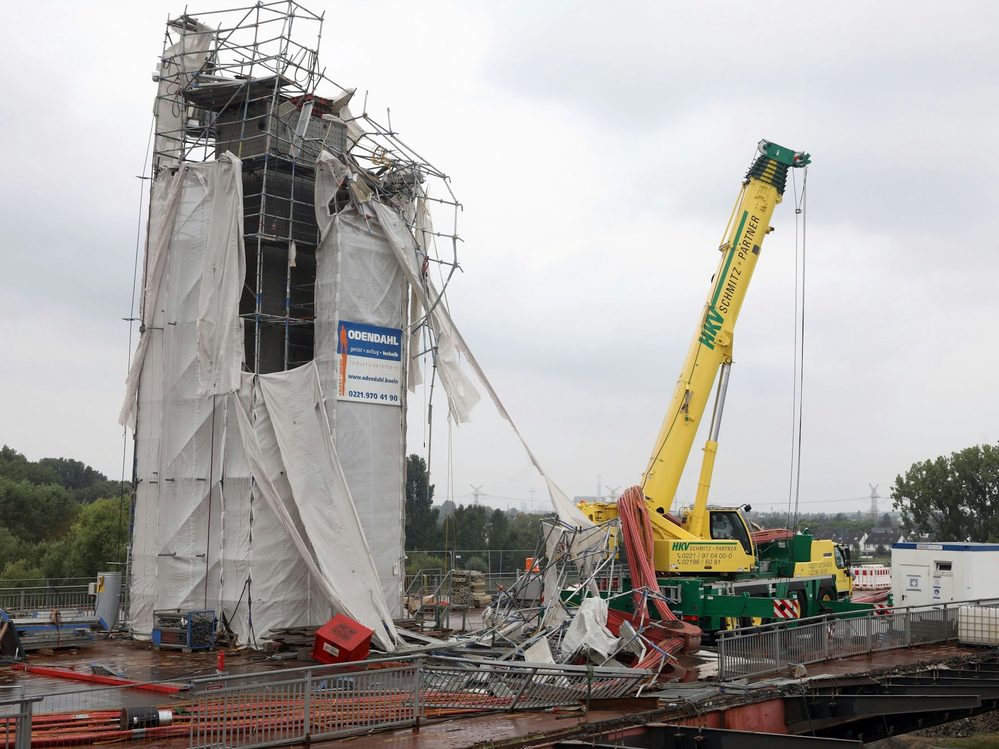 Ein Gerüst ist stark beschädigt, Teile sind herabgestürzt, liegen teilweise auf einem Kran.