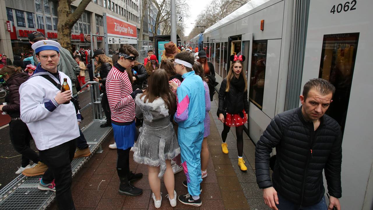 Menschen stehen verkleidet an einer KVB-Haltestelle in Köln.