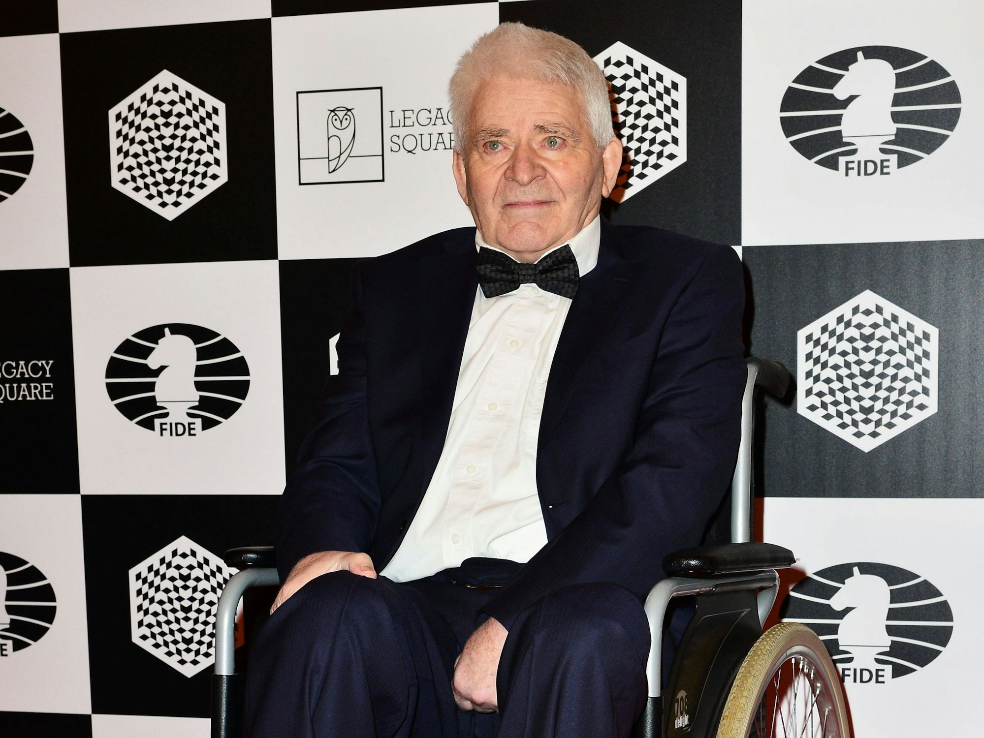 Boris Spasski sitzt auf dem Roten Teppich in einem Rollstuhl.