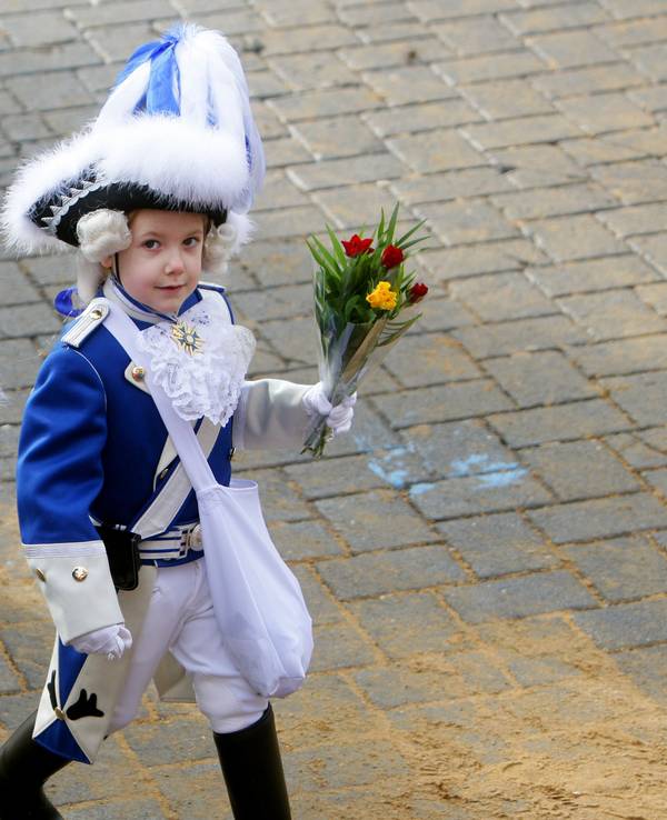 Ein kleiner Blauer Funke mit "Strüßje" (Blumen) geht in Köln beim Rosenmontagszug mit.