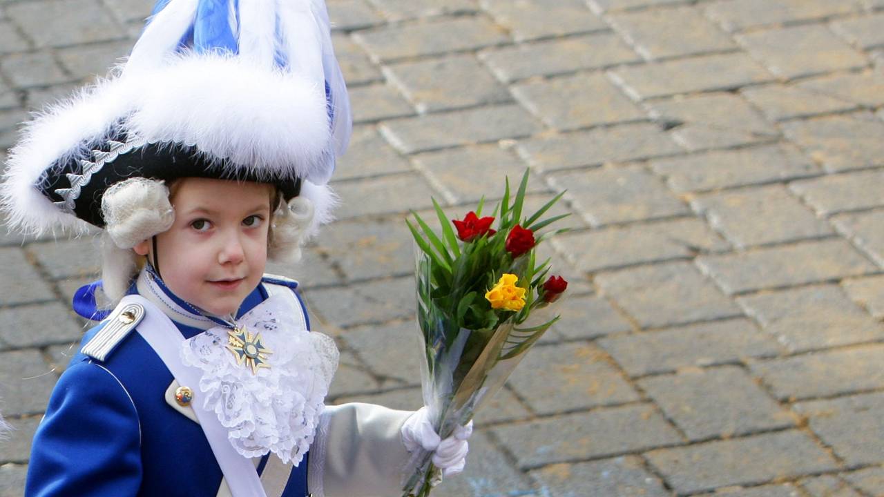 Ein kleiner Blauer Funke mit "Strüßje" (Blumen) geht in Köln beim Rosenmontagszug mit.