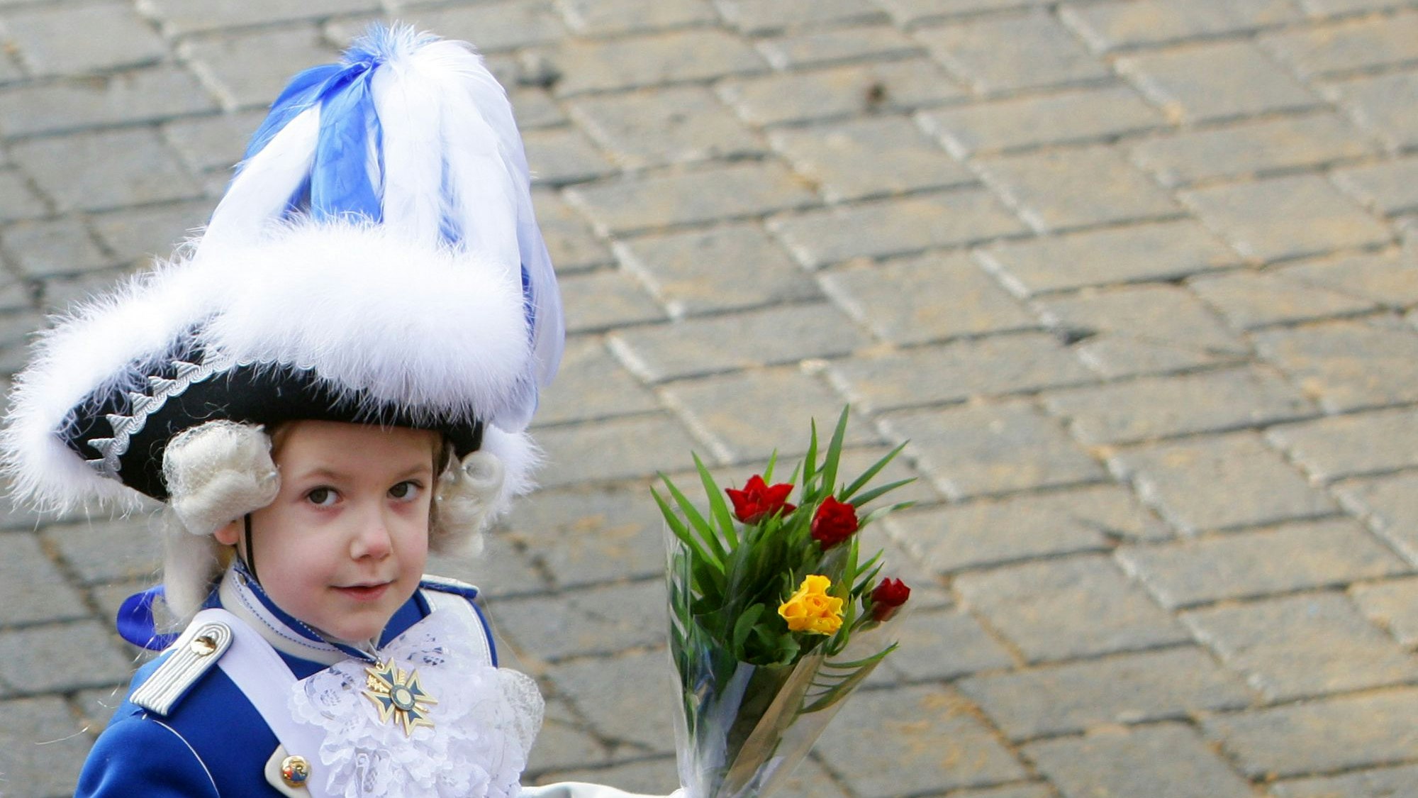 Ein kleiner Blauer Funke mit "Strüßje" (Blumen) geht in Köln beim Rosenmontagszug mit.