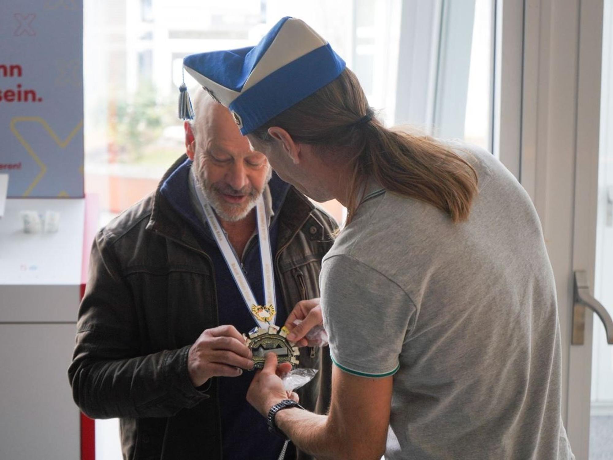 Ein Mann überreicht einem anderen Mann einen Karnevalsorden.