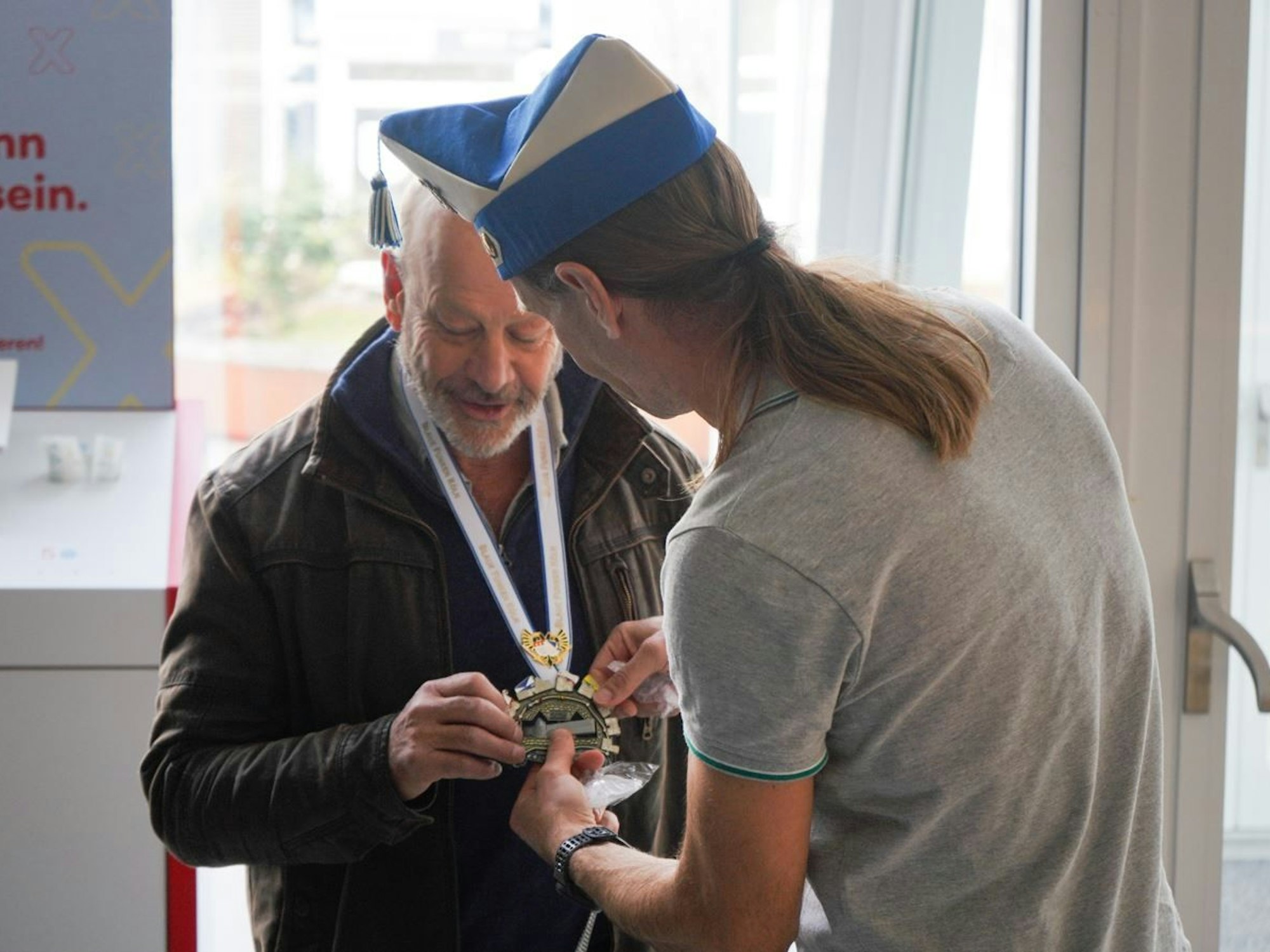 Ein Mann überreicht einem anderen Mann einen Karnevalsorden.