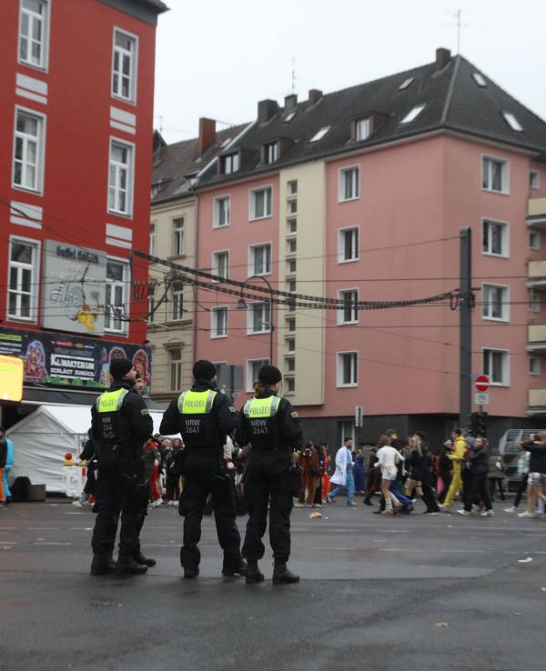 Einsatzkräfte der Polizei stehen an der Zülpicher Straße und verfolgen das Treiben an Weiberfastnacht in Köln.
