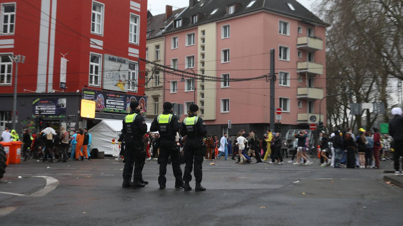 Einsatzkräfte der Polizei stehen an der Zülpicher Straße und verfolgen das Treiben an Weiberfastnacht in Köln.