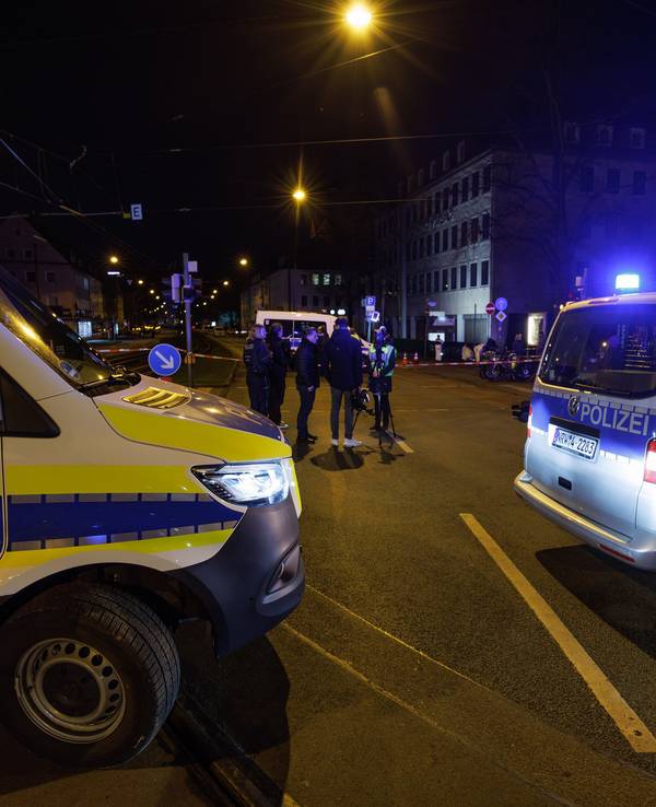 Einsatzfahrzeuge der Polizei stehen an einem Tatort, ein Bereich ist abgesperrt.