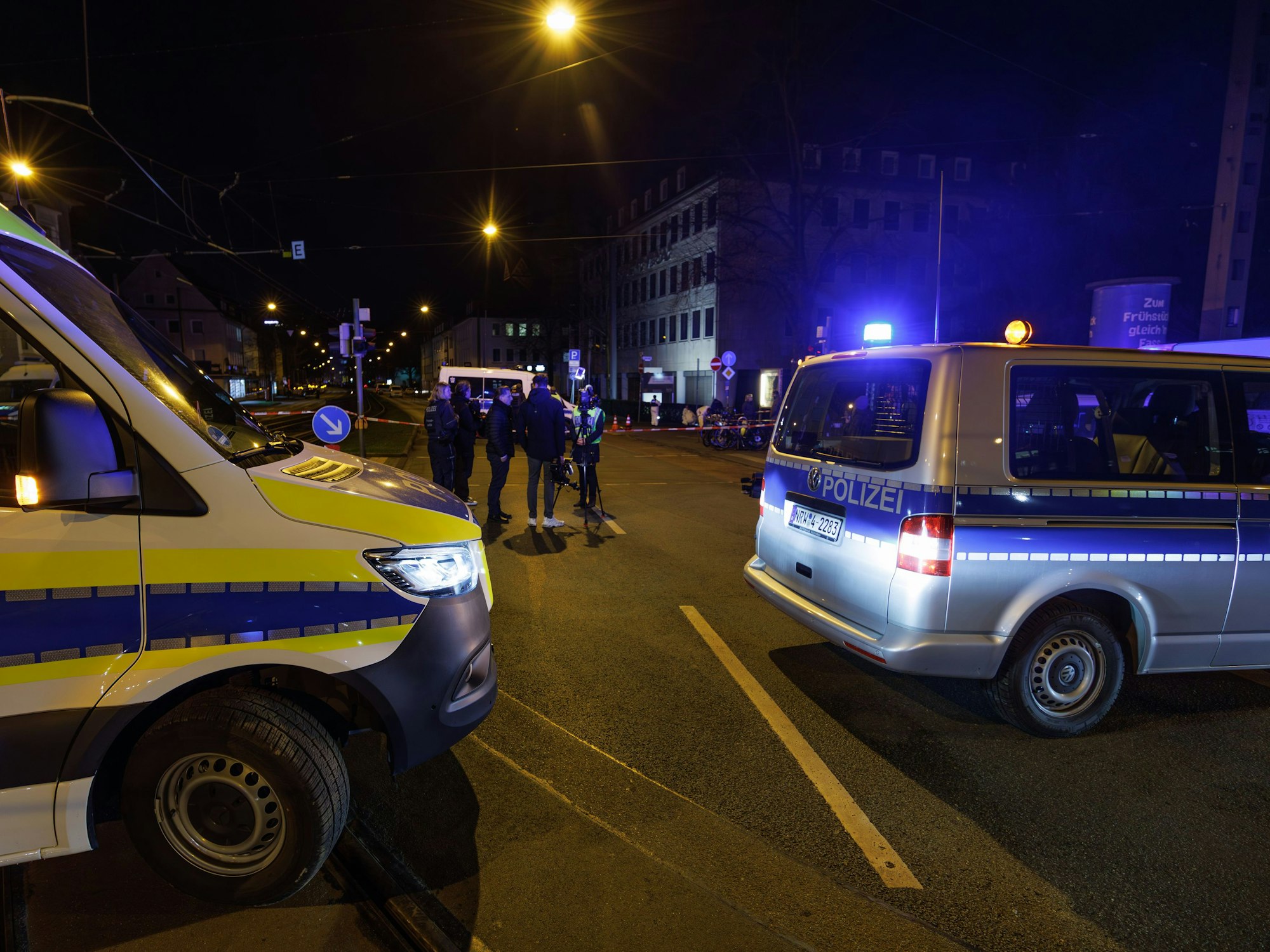 Einsatzfahrzeuge der Polizei stehen an einem Tatort, ein Bereich ist abgesperrt.