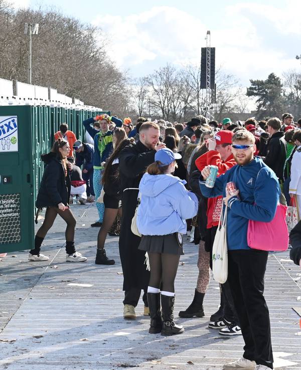 Menschen stehen an Weiberfastnacht vor den mobilen Toiletten an der Uniwiese.