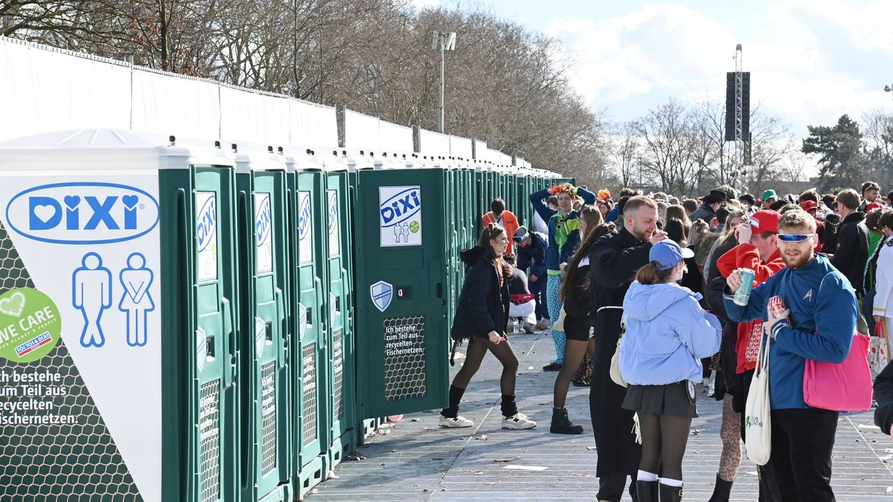 Menschen stehen an Weiberfastnacht vor den mobilen Toiletten an der Uniwiese.