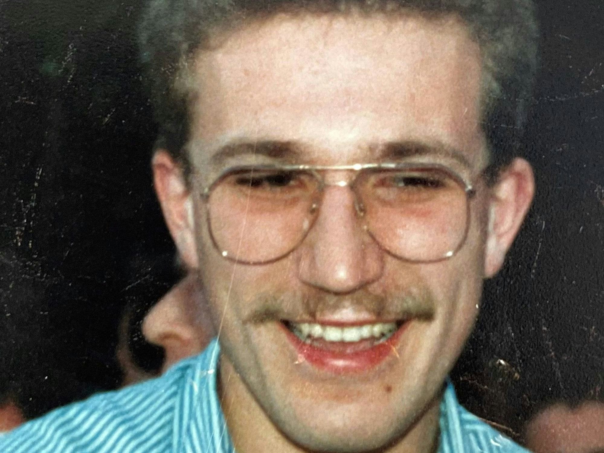 Ein junger Mann mit Brille lacht.