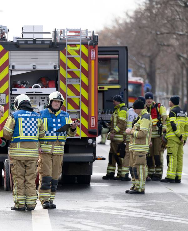 Einsatzkräfte der Feuerwehr stehen neben einem Löschfahrzeug.
