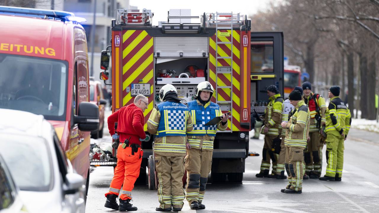 Einsatzkräfte der Feuerwehr stehen neben einem Löschfahrzeug.