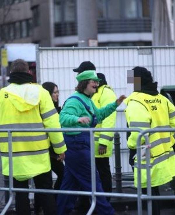 Drei Sicherheitskräfte stehen an einer Absperrung und kontrollieren Feiernde.