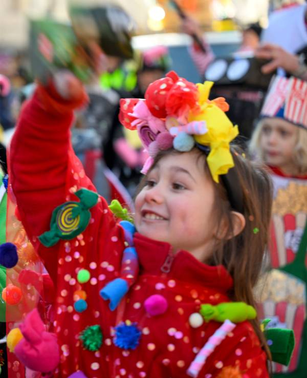 Ein verkleidetes Mädchen wirft eine Kamelle, ein anderes greift in eine Stofftasche.