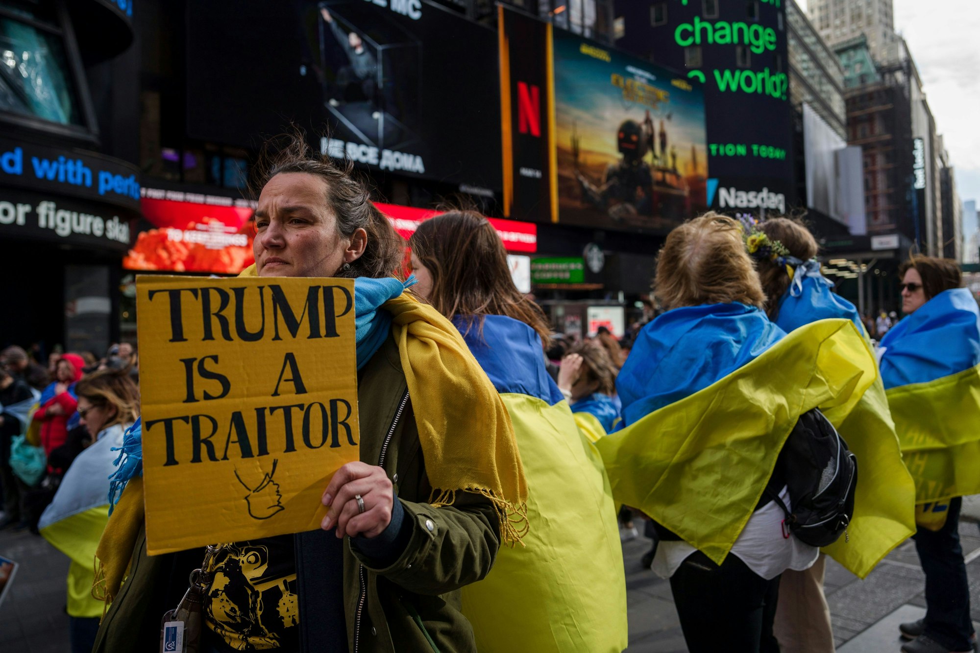 Eine Person hält ein Schild, während sich Mitglieder der ukrainischen Gemeinde und Unterstützende am Times Square in New York versammeln. Auf dem Schild steht auf englisch: „Trump ist ein Verräter.“