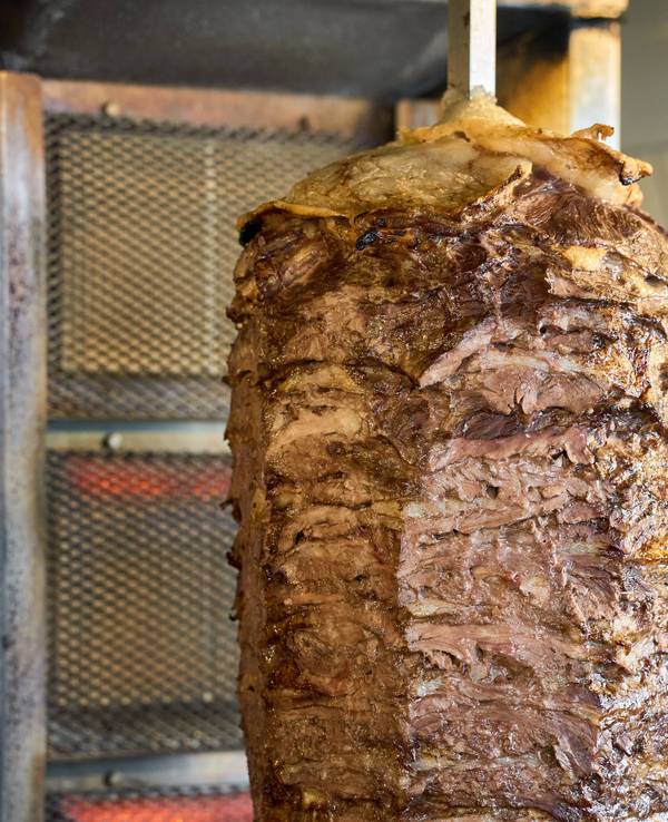 Zu sehen ist ein großer Döner-Spieß mit Rindfleisch, perfekt gegrillt und bereit für die Zubereitung von Döner Kebab.