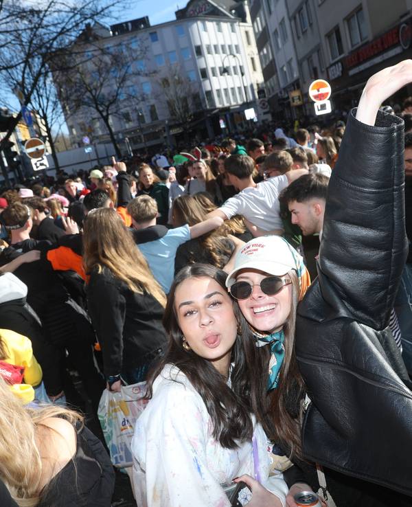 Zwei junge Frauen stehen vor einer größeren Menge Menschen.