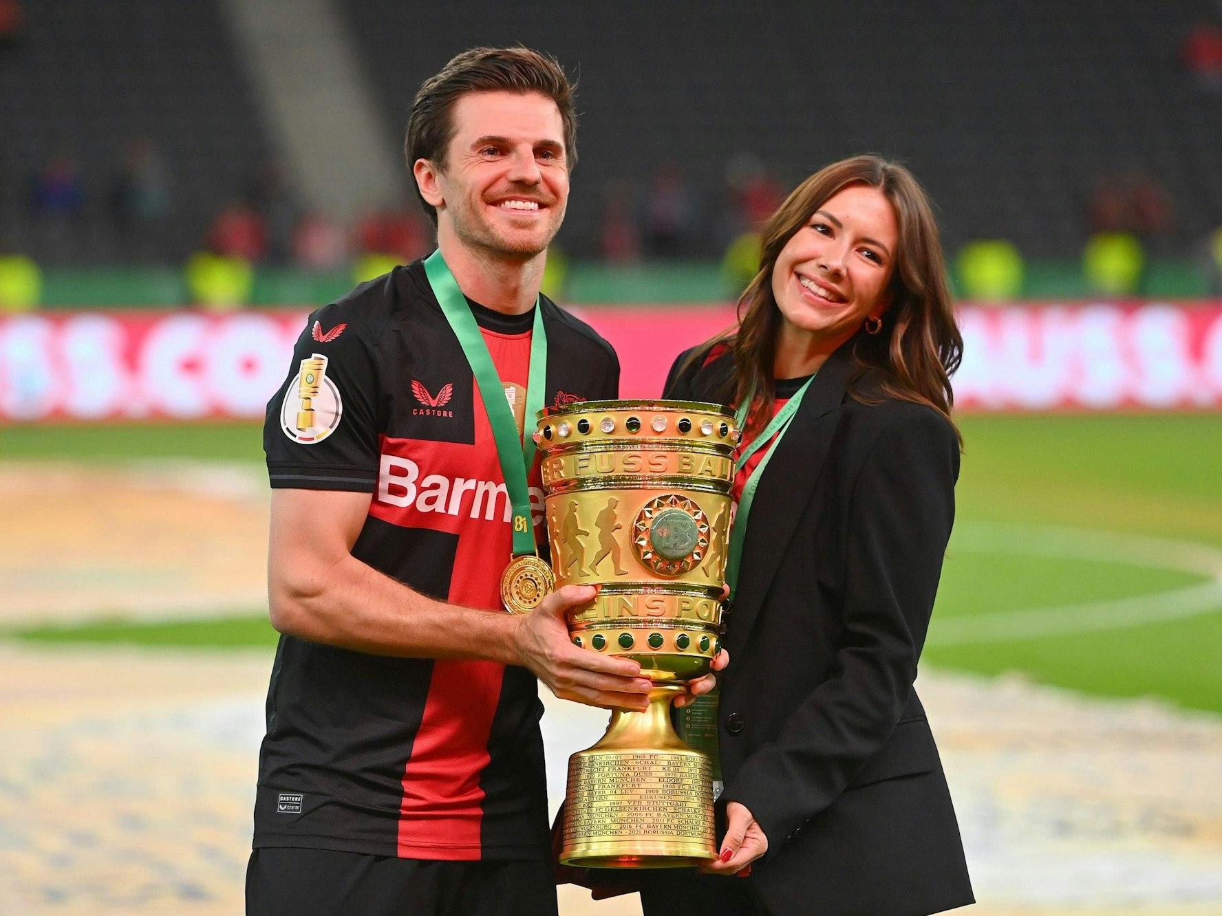 Jonas Hofmann und seine Frau Laura halten den DFB-Pokal in die Kamera.