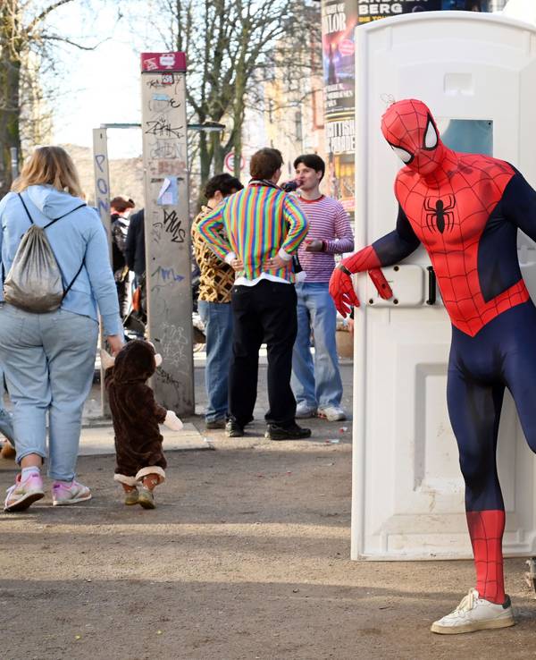 Ein Mann, der als Spiderman verkleidet ist, kommt aus einer Dixi-Toilette.