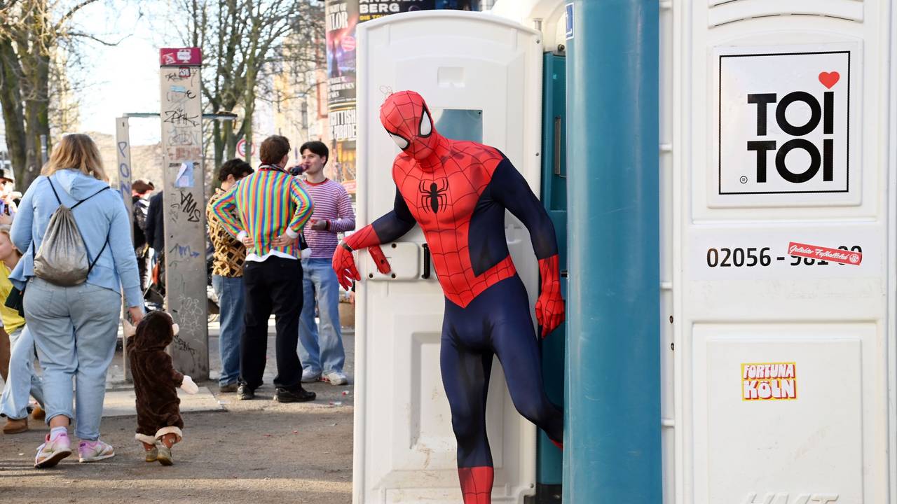 Ein Mann, der als Spiderman verkleidet ist, kommt aus einer Dixi-Toilette.