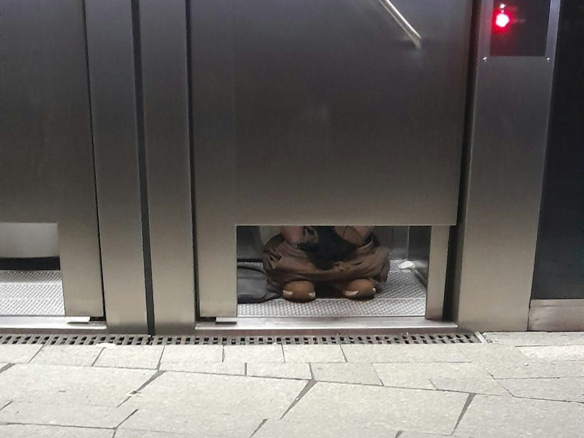 An einer öffentlichen Toilette in Köln sieht man die Füße eines Nutzers.