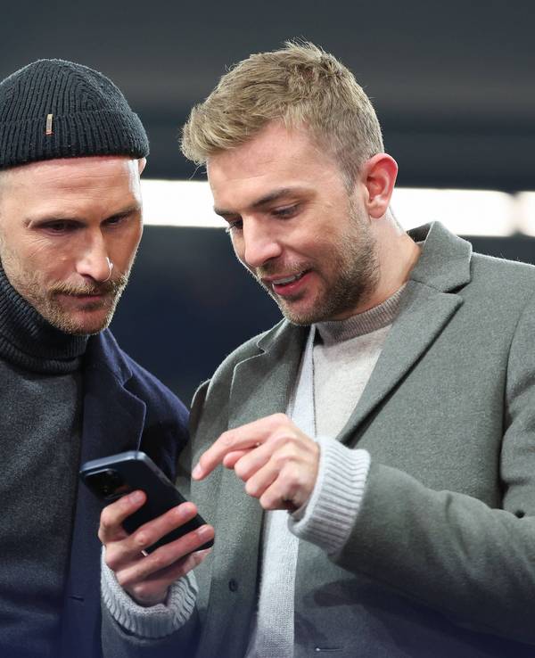 Benedikt Höwedes und Christoph Kramer gucken zusammen auf ein Handy.