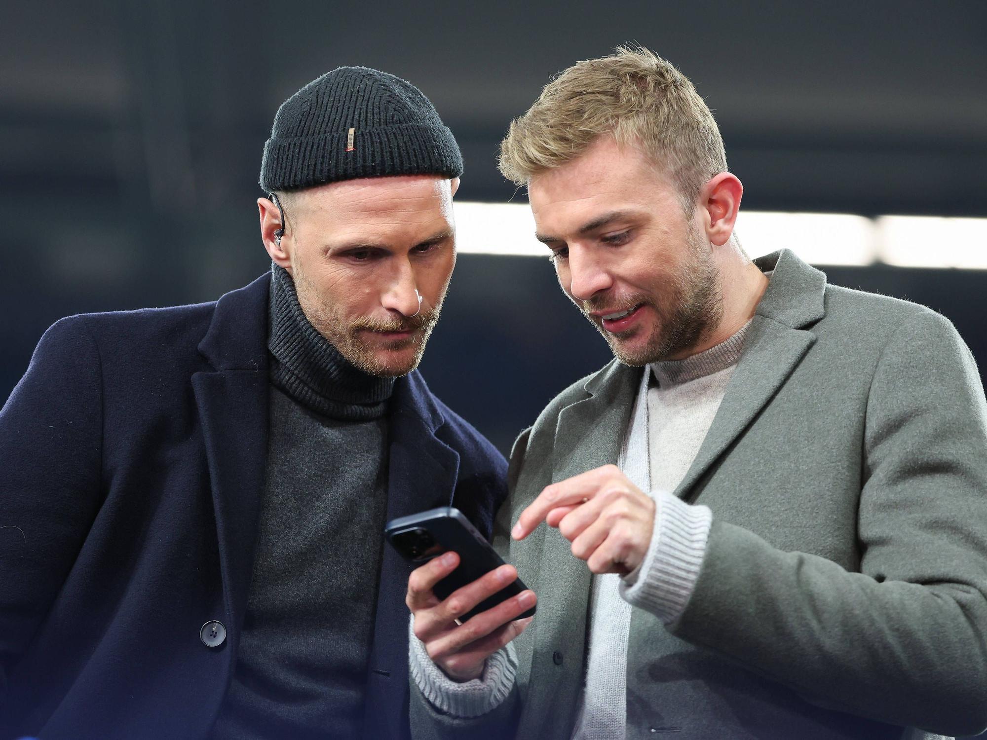 Benedikt Höwedes und Christoph Kramer gucken zusammen auf ein Handy.