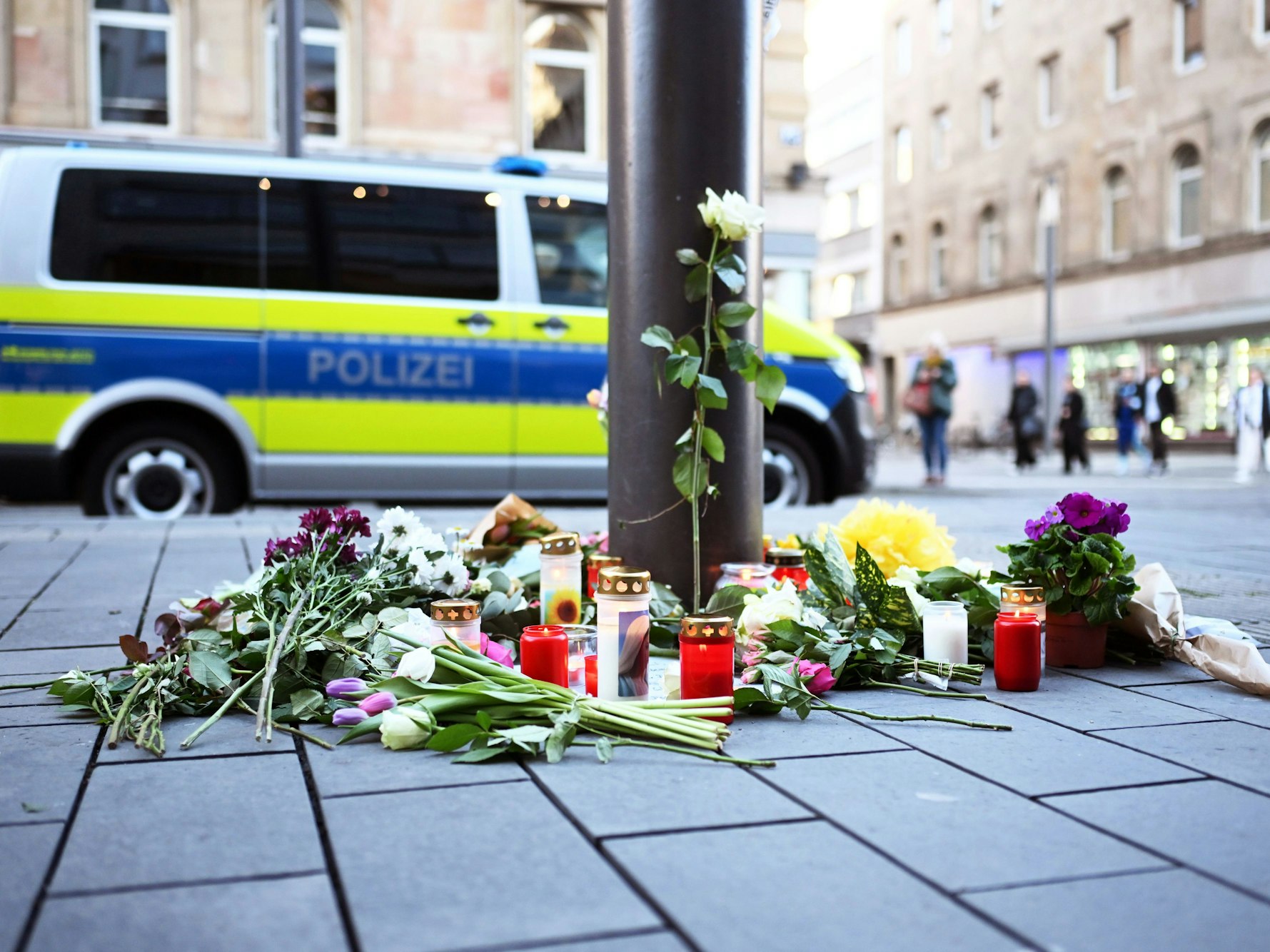 Kerzen und Blumen liegen in der Nähe des Paradeplatzes an einer Straßenbahn-Haltestelle in Mannheim. Am Vortag war ein Auto in eine Menschenmenge gefahren. Zwei Menschen starben, weitere wurden verletzt.