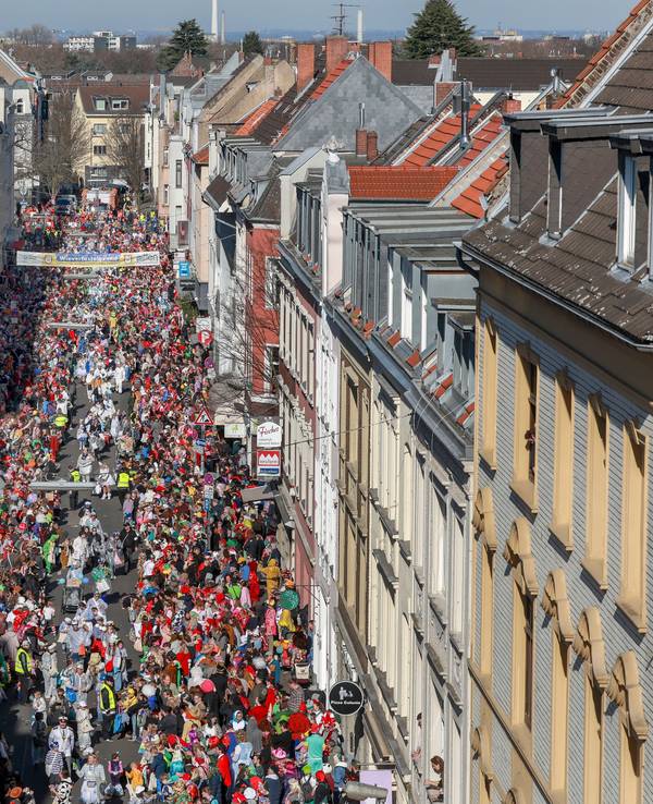 Menschen stehen an einem Karnevalsumzug am Straßenrand.